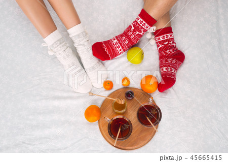 Soft photo of woman and man on the bed with tea and fruits, top view point. Female and male legs in Soft photo of woman and man on the bed with tea and fruits, top view point. Female and male legs in 45665415