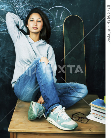 young cute teenage girl in classroom at blackboard seating on table smiling, modern hipster concept young cute teenage girl in classroom at blackboard seating on table smiling, modern hipster concept 45665728