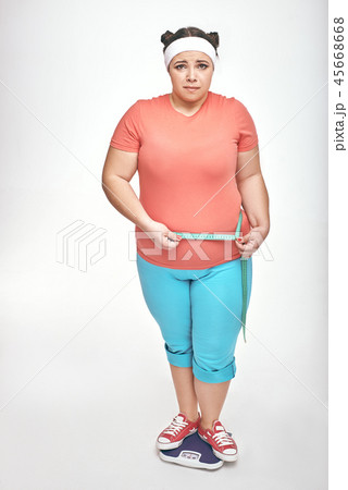 Chubby woman is measuring her belly on white background Chubby woman is measuring her belly on white background 45668668