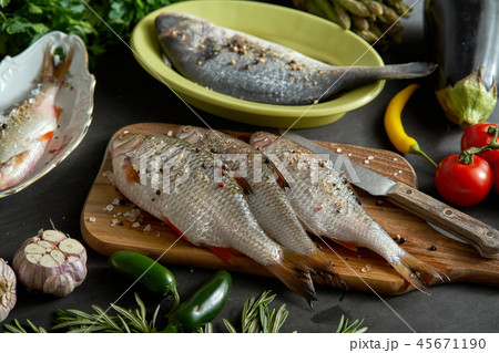 a set of fresh, raw fish in various dishes and with vegetables on a black table a set of fresh, raw fish in various dishes and with vegetables on a black table 45671190