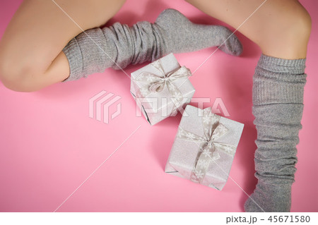 top view of slim female legs in warm gray socks with xmas gifts on a pink background 45671580