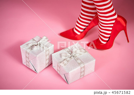 sexy santa woman's legs on a pink background and Christmas gifts 45671582
