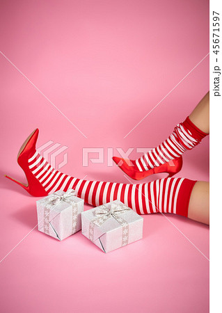 sexy santa woman's legs on a pink background and Christmas gifts 45671597
