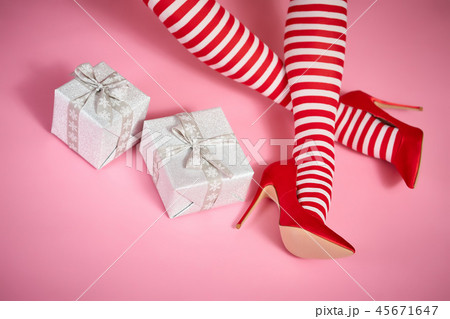 sexy santa woman's legs on a pink background and Christmas gifts 45671647