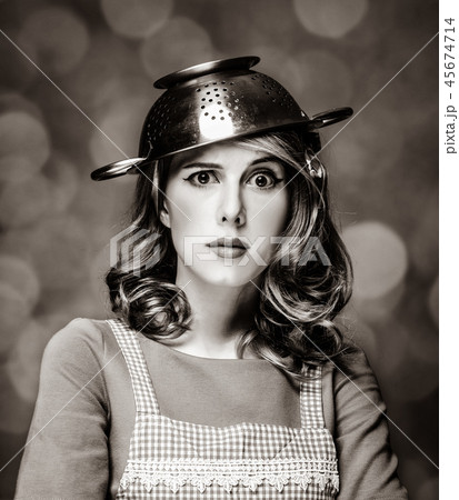 Surprised white housewife with colander on head 45674714