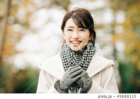 コートを着た日本人女性 冬の公園 笑顔の写真素材