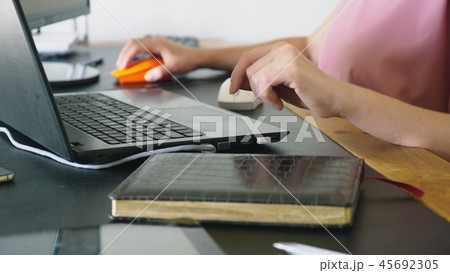 beautiful young woman working on a laptop and computer while sitting at a desk. 45692305