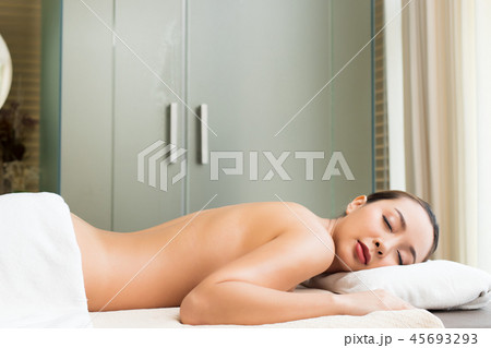 Body Massage on naked back of Mix Race Caucasian Asian woman, relaxing on bed and wait for professional spa. Therapist Spa body massage woman hands treatment on customer Body Massage on naked back of Mix Race Caucasian Asian woman, relaxing on bed and wait for professional spa. Therapist Spa body massage woman hands treatment on customer 45693293