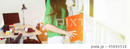 A young girl in the office pulls out folders with documents. 45693516