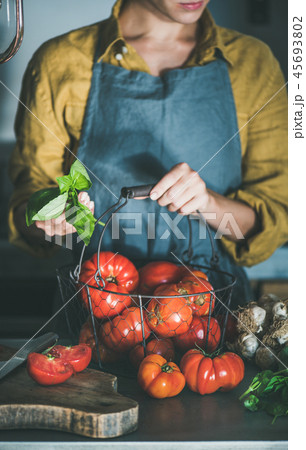 Woman in apron holding basket with heirloom tomatoes for cooking 45693802