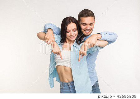 People and gesture concept - young pretty woman and handsome man pointing down over white background 45695809