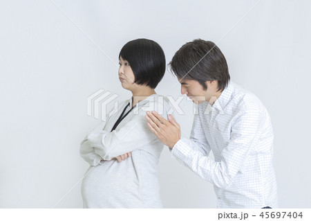 怒り顔の妊娠後期の妻に手を合わせて謝る(お願いする)夫。妊娠、夫婦、ケンカ、謝罪、お願いイメージ 怒り顔の妊娠後期の妻に手を合わせて謝る(お願いする)夫。妊娠、夫婦、ケンカ、謝罪、お願いイメージ 45697404