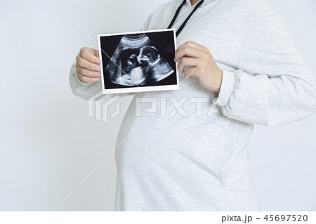 超音波エコーによる胎児の写真を見せる大きなお腹の妊婦 妊娠 胎児 健康 愛情 幸せイメージの写真素材