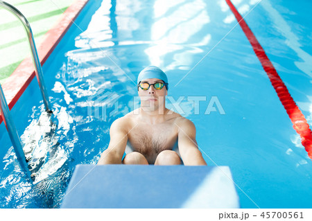 Image athlete man in blue rubber cap and glasses pushing in pool 45700561