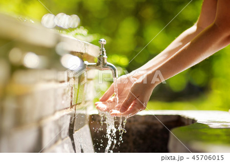 Woman washing hands in a city fountain 45706015
