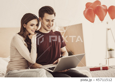 Romantic loving couple having movie night together while sitting on double bed 45711512