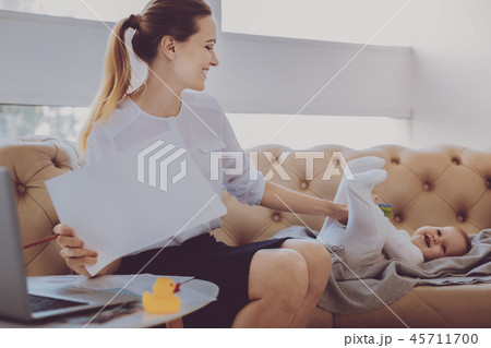 Businesswoman entertaining her cute smiling baby while working at home 45711700