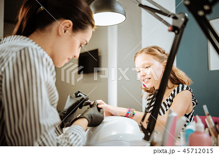 Mother working as nail artist making manicure for her cute teenage daughter Mother working as nail artist making manicure for her cute teenage daughter 45712015