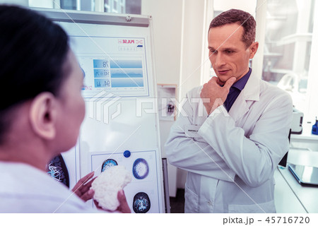 Attentive brunette man staring at model of brains 45716720