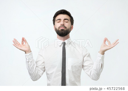 Concentrated bearded hispanic man with meditates, tries to relax after hard working day Concentrated bearded hispanic man with meditates, tries to relax after hard working day 45722568