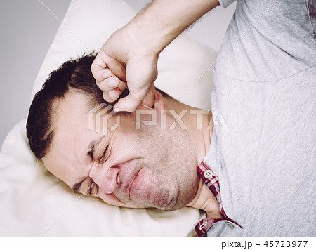 Sleepy man with pillow closing his ear 45723977
