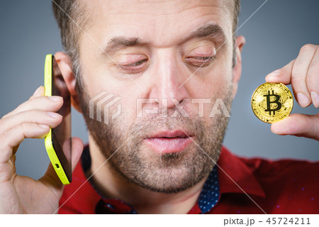 Man talking on phone holding bitcoin Man talking on phone holding bitcoin 45724211