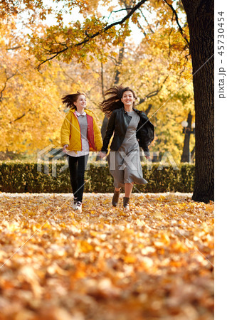 Two happy girls running in autumn city park. 45730454