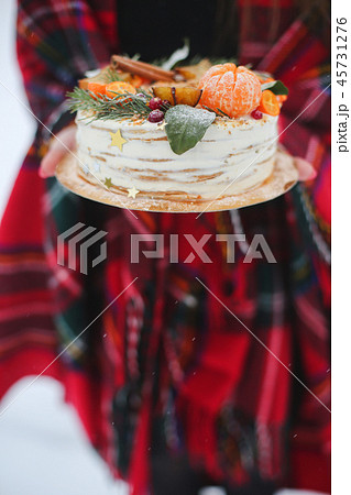 young woman holding a christmas cake in the street. it's snowing, sparkler 45731276
