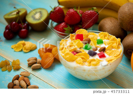 Tasty cornflakes with milk and fruits in glass bowl Tasty cornflakes with milk and fruits in glass bowl 45733311