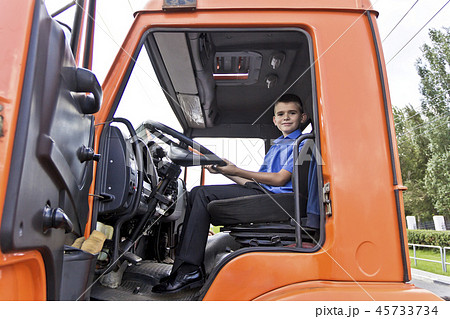 Boy sitting behind the wheel fire engine 45733734