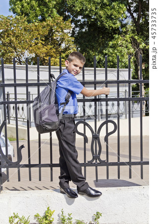 Boy hanging on the fence with school backpack 45733735