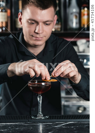bartender making Boulevardier Cocktail Finishing cocktail putting orange slice on top. Bar on a bartender making Boulevardier Cocktail Finishing cocktail putting orange slice on top. Bar on a 45734106