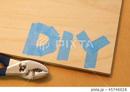 木の板の上にマスキングテープで書かれた「DIY」の文字と、工具。 45746028