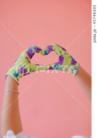 Closeup hands in gloves showing heart gesture by hands in pink monophonic background. Closeup hands in gloves showing heart gesture by hands in pink monophonic background. 45746305