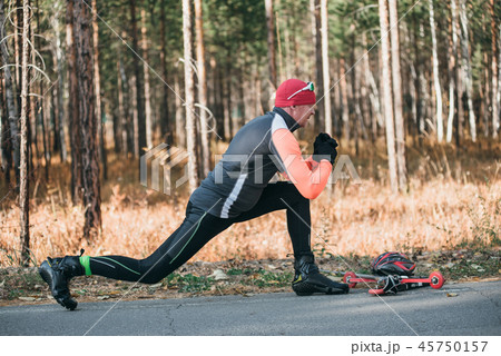 Training an athlete on the roller skaters. Biathlon ride on the roller skis with ski poles, in the Training an athlete on the roller skaters. Biathlon ride on the roller skis with ski poles, in the 45750157