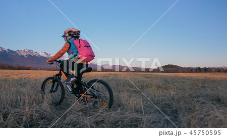 One caucasian children rides bike in wheat field. Little girl riding black orange cycle on One caucasian children rides bike in wheat field. Little girl riding black orange cycle on 45750595
