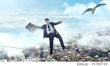 Businessman walking on a rope over business center 45760719