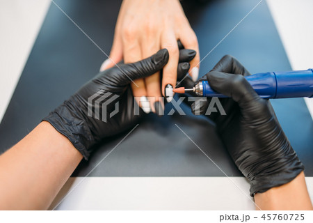 Beautician in gloves cleans old varnish from nails 45760725