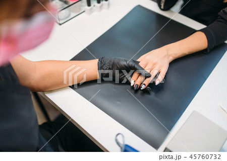 Beautician in gloves cleans old varnish from nails 45760732