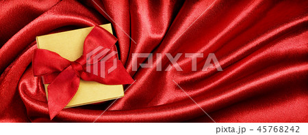 Holiday gift box with red ribbon bow on satin Holiday gift box with red ribbon bow on satin 45768242
