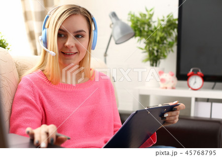 young beautiful blond woman sit on the sofa in livingroom hold binder in arms work with laptop 45768795