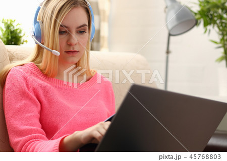 young beautiful blond woman sit on the sofa in livingroom hold binder in arms work with laptop 45768803