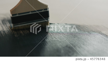 Brush painting plywood with black paint 45776348