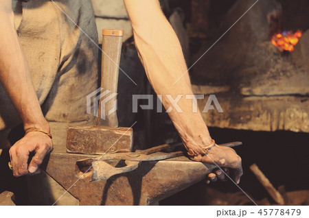 Blacksmith working metal with hammer 45778479