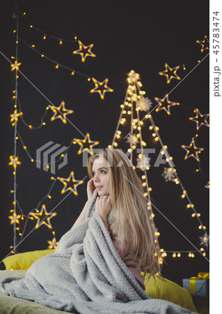 young woman in a plaid posing against the background of Christmas garlands. 45783474