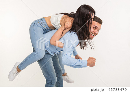Relationship and fun concept - Happy man carrying his girlfriend on the back on white background 45783479