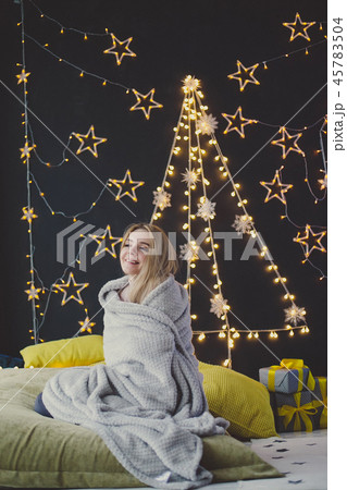 young woman in a plaid posing against the background of Christmas garlands. 45783504