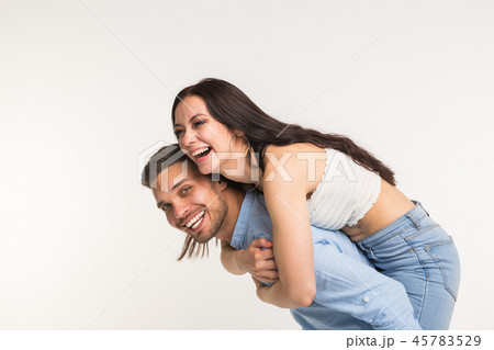 Emotional, love and people concept - young woman climbed the guy on the back and they happy and 45783529