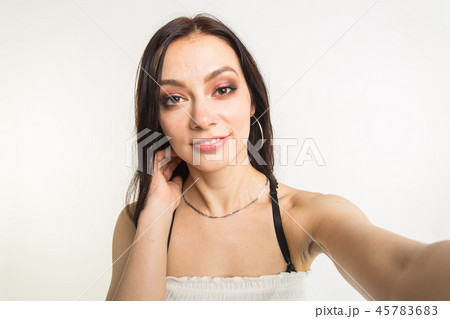 Close-up of young beautiful woman taking selfie on white background Close-up of young beautiful woman taking selfie on white background 45783683