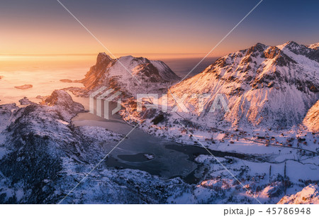 Aerial view of snowy mountains, blue sea at sunset 45786948